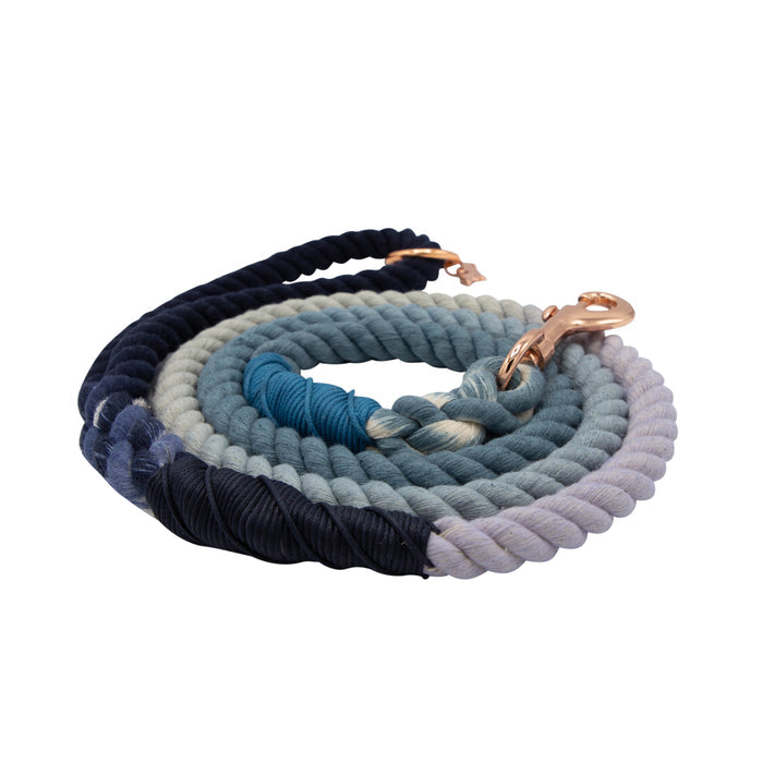 The Sassy Woof Dog Rope Leash - Oasis is a hand-crafted cotton leash in navy, blue, and light gray ombre with a rose gold clasp, shown coiled on a white background.
