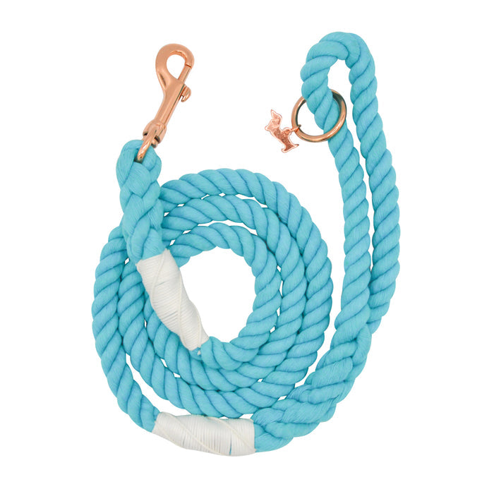 The Sassy Woof Dog Rope Leash - Seaside is a coiled turquoise cotton leash with white accents, rose gold hardware, and a circular ring for attaching accessories.