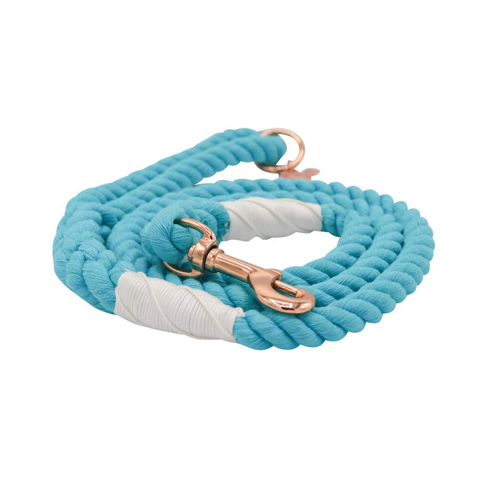 The Sassy Woof Dog Rope Leash - Seaside features turquoise cotton rope with white accents, elegant rose gold hardware, a coiled design, and sturdy clasp—perfect for stylish walks.