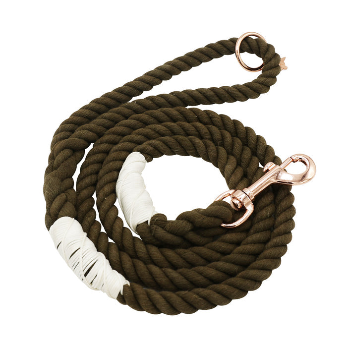 The Sassy Woof Dog Rope Leash - Walnut features a coiled dark green cotton rope with white wrapped accents, finished with a rose gold metal clip and ring, shown on a white background.