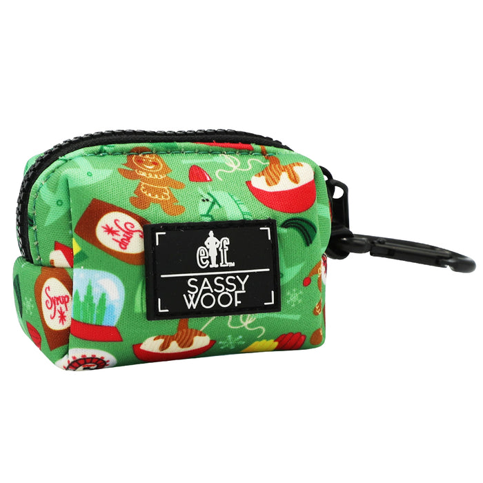 The Dog Waste Bag Holder - Elf™ by Sassy Woof is a small green neoprene pouch with festive holiday prints, a zippered closure, “Sassy Woof” label, and black clip for easy leash attachment; perfect as a stylish pet accessory.
