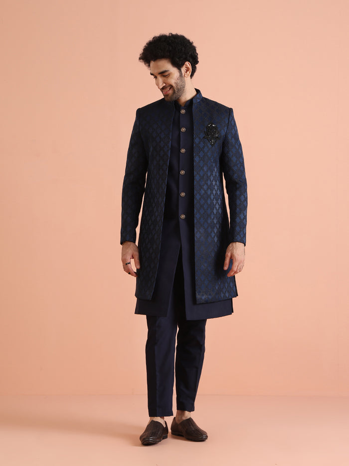 The model is standing straight, posing in Kisah's Navy Blue Silk Blend Indo Western Sherwani Set for men